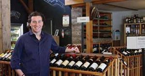 Gavin Fine smiling in front of wine rack