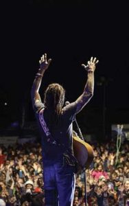 concert performer arms raised looking out at crowd